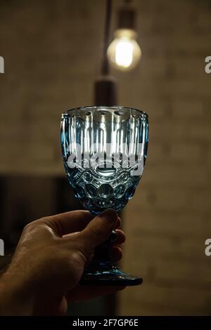 Glas mit Wasser in der Hand draußen und beleuchtete Lampe Hinter Stockfoto