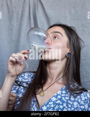 Weiße junge Frau isoliert auf dunkelgrauem Trinken Stockfoto