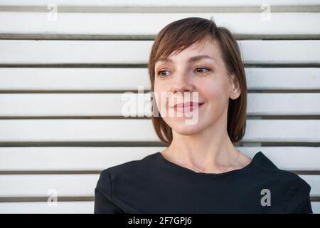 Porträt einer Frau mit kurzen Haaren auf einem weißen Holzhintergrund Stockfoto