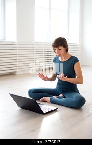 Frau in Sportkleidung sitzt vor einem Laptop und Kommuniziert Stockfoto