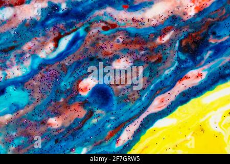 Der Hintergrund ist Acrylblau mit roten und rosafarbenen Flecken, die mit Funkeln bestreut sind. Farbenfrohe Marmorstruktur. Flüssiger Marmor. Kunstbild. Avant-gard Stockfoto