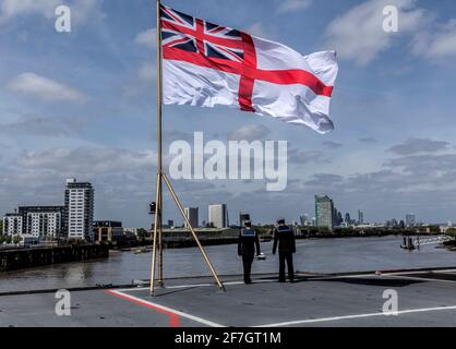 Zwei Matrosen auf dem Deck der HMS Ocean unter einem Die große Union Jack und St Georges Flag blicken auf die City of London Stockfoto