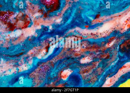 Der Hintergrund ist Acrylblau mit roten und rosafarbenen Flecken, die mit Funkeln bestreut sind. Farbenfrohe Marmorstruktur. Flüssiger Marmor. Kunstbild. Avant-gard Stockfoto