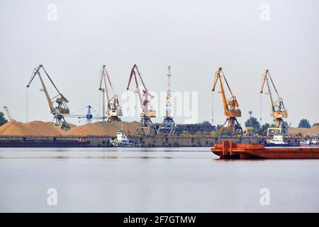 Industrielle Flusslandschaft mit Frachtterminal und Anlegestelle für Schlepper und Großkähne Stockfoto