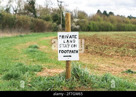 „Privatland“, „Stay on Footpath“-Schilder entlang eines öffentlichen Wegs, das durch Ackerland führt. Oxfordshire, Großbritannien Stockfoto