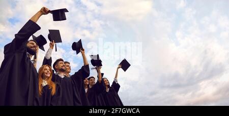 Millennials-Studenten feiern die Abschlussfeier und werfen ihre Mütze auf. Junge Menschen am Tag des Beginns Stockfoto