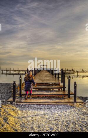 Holzsteg im Wasser des Sees. Ein Kind läuft am Pier. Stockfoto