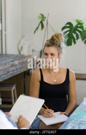 Junge schöne blonde weibliche bildende Künstler Zeichnung im Studio. Stockfoto