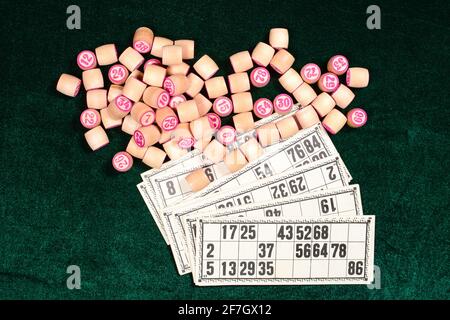 Lotto, klassisches Familien-Brettspiel. Holzfässer mit Zahlen und Karten auf einer grünen Samtfläche während des Spiels. Vintage-Spiel, Bingo. Stockfoto