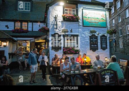 Menschen, die vor dem Pub Sloop Inn in St. Ive's Harbour, Cornwall, Großbritannien, sitzen. Stockfoto