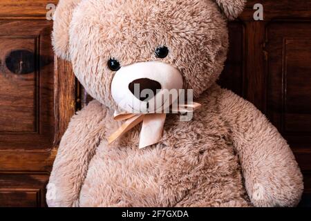 In Toronto, Ontario, Kanada, schlingt ein riesiger beiger Teddybär mit goldenem Bogen gegen ein Mahagoni-Kopfteil. Stockfoto