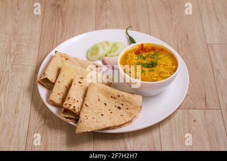 Indische Küche sev Kadhi chapati - Vegetarische Curry aus Buttermilch, sev und Kichererbsenmehl. Serviert in einer Schüssel oder Karahi auf Holzhintergrund, Sel Stockfoto