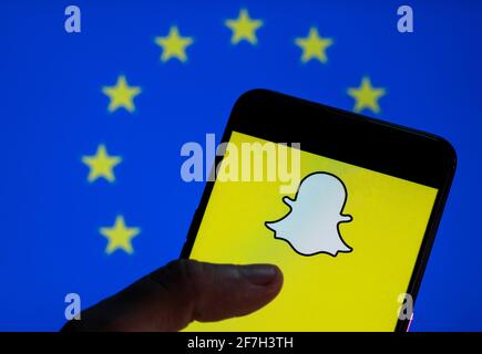 In dieser Abbildung ist das Snapchat-Logo für Multimedia-Nachrichten auf einem Bildschirm für mobile Android-Geräte mit der Flagge der Europäischen Union (EU) im Hintergrund zu sehen. Stockfoto