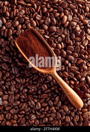 Holzlöffel mit gemahlenem Kaffee auf dem Hintergrund der Bohnen Stockfoto