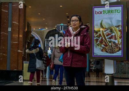 Niagara, Kanada, März 2018 - eine junge Frau asiatischer Herkunft macht ein Selfie mit einem Stockhalter, während sie in einem Einkaufszentrum steht Stockfoto