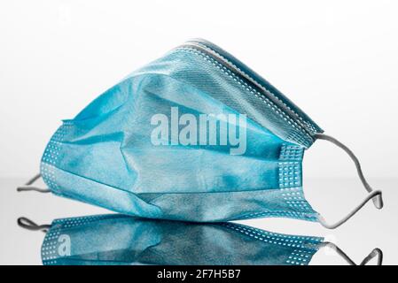 Chirurgische Maske mit Gummi-Ohrbändern. Eine typische dreischichtige OP-Maske, um Mund und Nase zu bedecken. Schutz vor Bakterien. Schutzkonzept Stockfoto