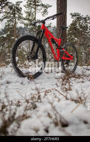 Enduro 27,5 Mountainbike in rot ruht an einem kalten, verschneiten Wintertag auf einer Bike Single Track. Konzept des Extremsports oder Mountainbiken in der Kälte Stockfoto