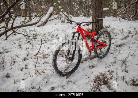 Enduro 27,5 Mountainbike in rot ruht an einem kalten, verschneiten Wintertag auf einer Bike Single Track. Konzept des Extremsports oder Mountainbiken in der Kälte Stockfoto