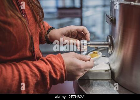 Hände einer Frau, die einen industriellen Spender für Sauce verwendet. Stockfoto