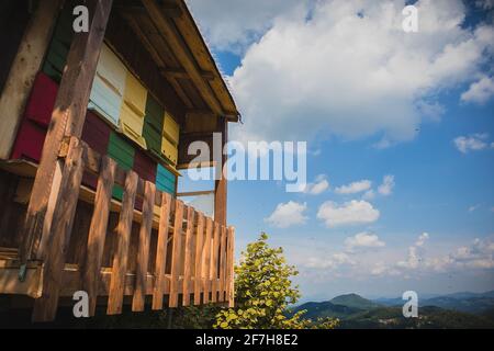 Altes Holzhaus, das als moderner Bienenstock dient. Bunte Bienenstöcke mit Bienen, die an einem sonnigen Tag herauskommen. Stockfoto