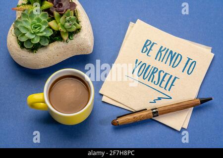 Seien Sie freundlich zu sich selbst - inspirierende Handschrift auf einer Serviette mit einer Tasse Kaffee, Selbstpflegekonzept Stockfoto