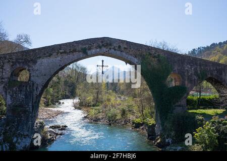 Alte römische Brücke in Cangas de Onis, Asturien, mit einem Kreuz, das an ihr hängt, als Symbol des Sieges Stockfoto