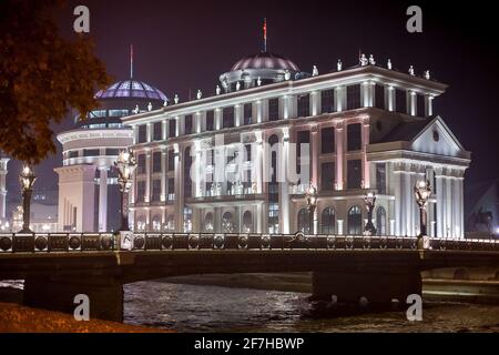 Das Außenministerium in Skopje, Mazedonien, während der Nacht. Gebäude umgeben von Lichtern und mit Blick auf die Brücke. Stockfoto