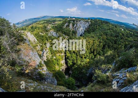 UNESCO-Weltkulturerbe Skocjanske jame mit einer weiten Fischauge aufgenommen. Blick auf die tiefe Schlucht mit Höhleneingang und Spazierwegen. Villa Stockfoto