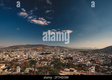 Panorama von Oaxaca, Mexiko, an einem sonnigen Tag mit blauem Himmel, Blick von der Benito Juarez Statue über der Stadt. In der Mitte sind einige weiße Wolken zu sehen Stockfoto