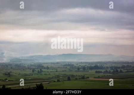 Regenpanorama über Greeb Ebenen und Felder von ljubljana Sümpfen und mit Wolken und Bergen im Hintergrund und Blumen im Vordergrund. Stockfoto