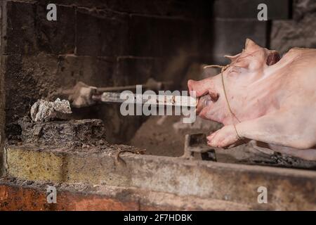 Schwein auf einem Metallstab wird vorbereitet, um auf einem traditionellen balkan-Grill namens rostilj oder odojek gedreht zu werden. Frisches Schwein wartet auf einen Grill. Detail der Stange Stockfoto