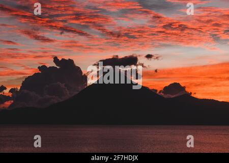 Abendansicht der Silhouette des Vulkans San Pedro mit Blick auf den Atitlan-See in Guatemala. Interessante Wolkenformationen über dem Vulkan. Stockfoto