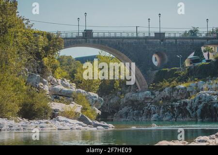 Berühmte Brücke auf Kanal ob Soci Dorf während des heißen Sommertages mit kaltem Soca Fluss fließt unter der Brücke. Froschansicht einer Brücke im Kanal. Stockfoto