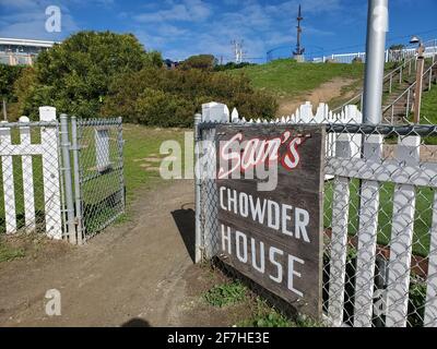 Abgewinkelte Aufnahme eines Zauns mit einem Schild „Sam's Chowder House“ und einem offenen Tor mit einem unbefestigten Pfad und einer Treppe, die zu einem Küstengang und zum Pillar Point Harbour Beach in Half Moon Bay, Kalifornien, führt, 30. Januar 2021. (Foto von Smith Collection/Gado/Sipa USA) Stockfoto