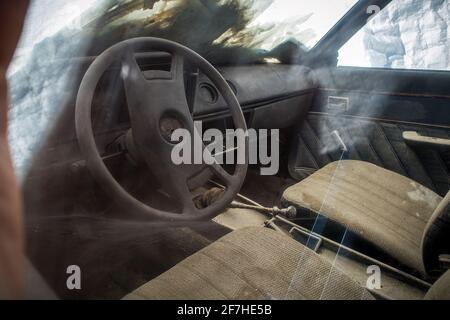 Das Innere eines verlassenen oder vergessenen Oldtimer-Autos, das auf dem Feld sitzt und verrottet. Sitze und Polster mit Armaturenbrett mit Spinne w bedeckt Stockfoto