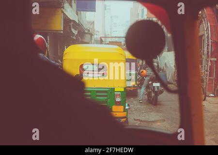 Fahren Sie in einem Tuk Tuk oder Rikshaw in den indischen Straßen von Neu Delhi. Verrückte Fahrt im Verkehr in überverschmutztem Delhi. Bunte Rikschas reiten durch Höhlen Stockfoto