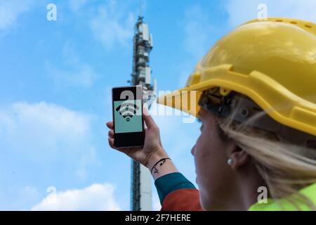 5G-Netz. Mobile Internet-Radioantenne. Funkturm. Radiowellen und das Internet. Ingenieurin Frau mit einem Smartphone mit 5 G Wireless High Speed Stockfoto