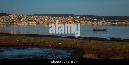 Panorama der Stadt Sant Antioco mit einer Lagune und einem Fischerboot, das auf der esea zu sehen ist. Romantisches, sonniges Morgenbild eines Dorfes auf Sardinien. Stockfoto