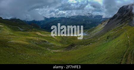 Panorama vom Großglockner Passan einem Sommertag mit schönen Wolken, grünen Wiesen und kurvenreichen Straße unten gesehen. Sommer auf Bergpass. Stockfoto