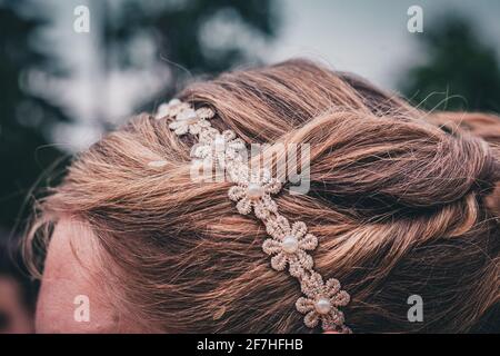 Detail eines floralen Haarzubehörs auf blondem hellbraunem Haar. Stockfoto