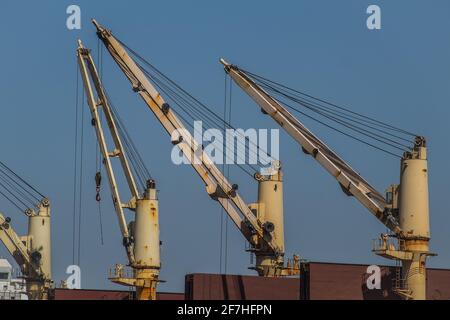 Ein Satz weißer Krane oder Aufzüge, die auf einem Frachtschiff montiert sind. Stockfoto