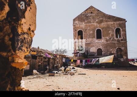 Ein altes verlassene Haus mit Kasernen vorne und einer Reihe von Kleidungsstücken, die in der Sonne auf der Sklaveninsel Goree in der Nähe von Dakar, Senegal, trocknen. Stockfoto