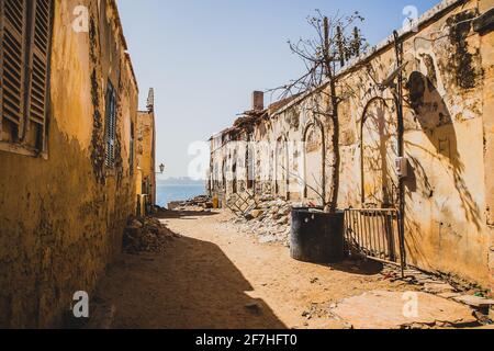 Eine der weniger attraktiven Straßen auf der berühmten Sklaveninsel Goree. Reihe von Häusern mit Schmutz und Müll auf dem Boden. Stadt Dakar ist in der b gesehen Stockfoto