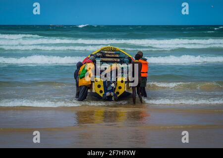 Typische Fischerboote in Yoff Dakar, Senegal, genannt Pirogue oder Piragua oder Piraga. Farbenfrohe Boote, die von Fischern benutzt werden, werden in den atlantik geschoben Stockfoto