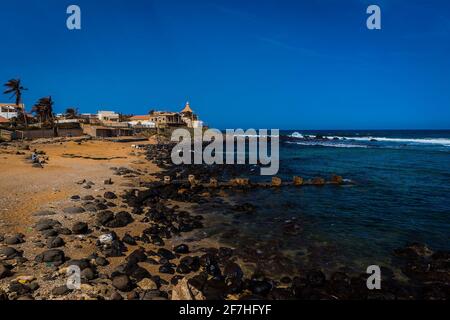 Strand mit blauem Wasser und felsiger und sandiger Küste im Vorort Tonghor in Dakar, Senegal. Afrikanischer Strand in Dakar an einem sonnigen Tag. Stockfoto