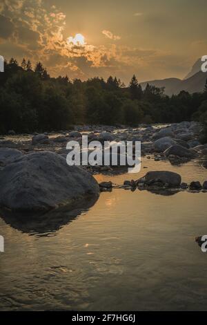 Schöner Sommerabend mit Sonne gerade untergehen behnd julischen alpen und Fluss in Resia Region oder Rezija, in der Nähe von Resciutta Dorf. Steine im W Stockfoto