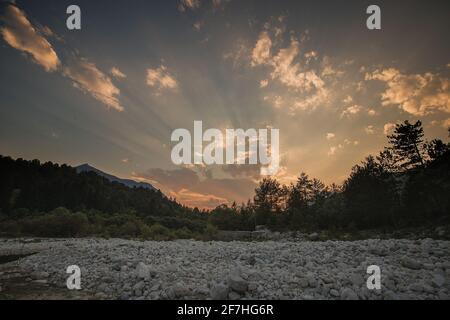 Schöner Sommerabend mit Sonne gerade untergehen behnd julischen alpen und Fluss in Resia Region oder Rezija, in der Nähe von Resciutta Dorf. Steine im W Stockfoto