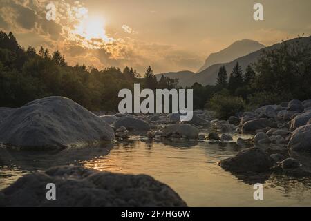 Schöner Sommerabend mit Sonne gerade untergehen behnd julischen alpen und Fluss in Resia Region oder Rezija, in der Nähe von Resciutta Dorf. Steine im W Stockfoto