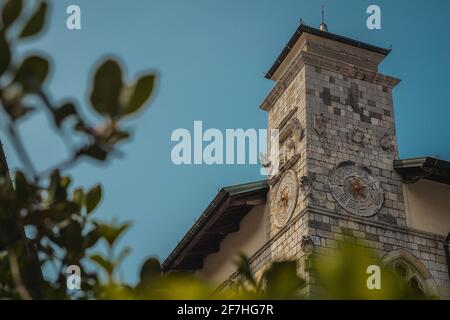 Turm des Pallazo comunale oder Rathaus in der Altstadt von Venzone in norditalien, aus der niedrigen Perspektive durch die grünen Büsche betrachtet Stockfoto