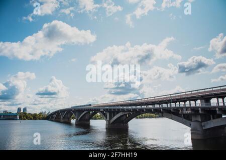 An einem warmen Sommertag in der Ukraine fährt die U-Bahn in Kiew über die Brücke über den Fluss Dnjepr in Richtung Hydropark und Dnipro. Stockfoto
